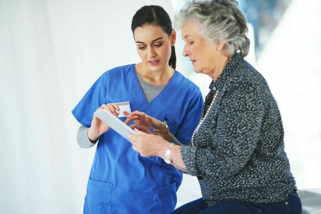 Senior woman reviewing medical chart with nurse